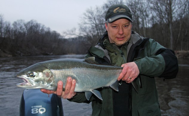 Aaron Kamphuis, of Rockford, hoists up a nice silver steelhead caught on the Muskegon River. 