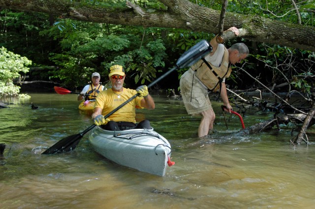 Association members Bill Hoenes, center, and Bill McKinney, back, paddle past Dick Curtis while he works to clear a segment of the water trail on the Black River. Photo: Howard Meyerson