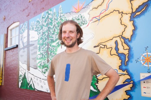 Luke Jordan enjoys the Trail Town celebration recently held in Lowell, Michigan where a new NCT mural was unveiled behind him. The blue blaze on his T-shirt is similar to the markings found along the trail letting hikers know they are on the right path. Photo Brandon Mulnix