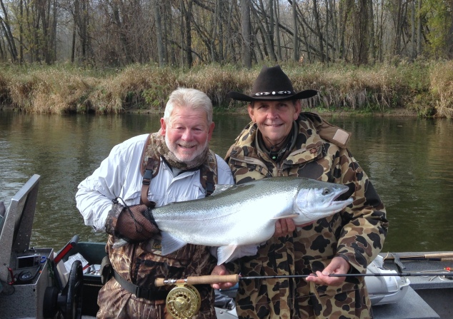 Fishing guide, Chuck Scribner (left) helps his client and friend, Bill Fuhs hold up the 38-inch steelhead Fuhs caught on the Big Manistee River last fall. (Courtesy | Captain Chuck Scribner)