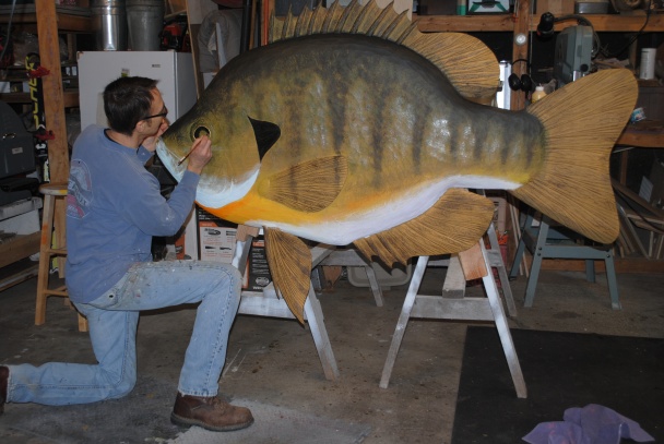 Bob Batchik works in his studio to finish painting a large bluegill wood carving for a client. (Courtesy | Bob Batchik, Sunfish Woodworks)