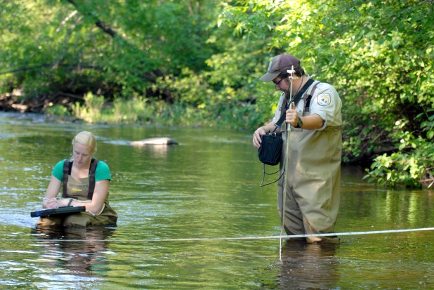  Sea lamprey researchers measure stream velocity and discharge in the Carp Lake River to determine the appropriate concentration of alarm substance to apply.  Photo: Tom Luhring, Michigan State University.