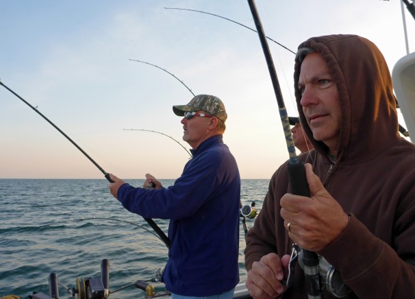 David Kostecki, from Oakville MO (left) and Stan Kostecki (right),from Defiance MO, work to reel in two salmon as Captain Russ Clark looks on. Photo: Howard Meyerso