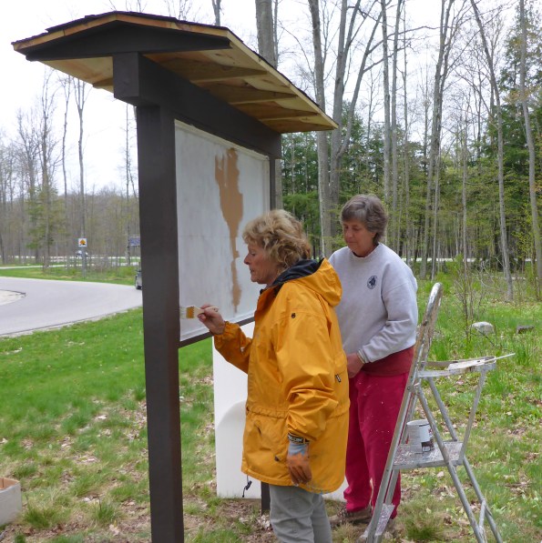  Grand Traverse Hiking Club volunteers, Deena Barshney (left) and Marilyn Hoodstraten, help paint a new trailhead kiosk for the North Country Trail. Photo: Howard Meyerson