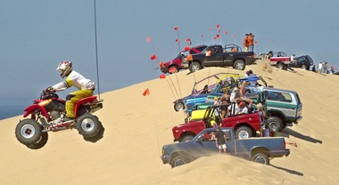 A quad-runner gets some air as ORV's sit at the top of the highest dune at the Silver Lake State Park off-road vehicle area. Noise and congestion near the park have brought changes in gaining park entrance (Chris Clark/THE GRAND RAPIDS PRESS)
