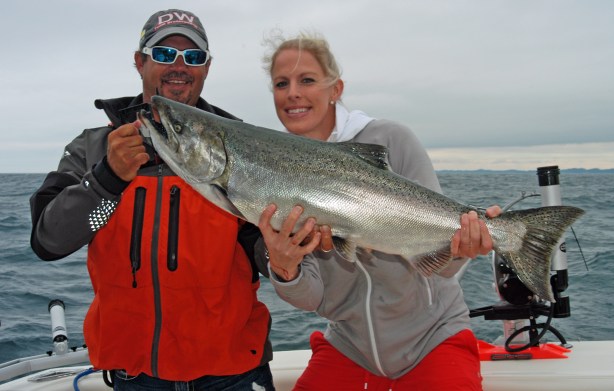 Captain Brian Butts, owner of Sea Flea Charters, helps Ashley Wiersma hold a big salmon she caught while fishing Lake Michigan in 2013. Far fewer that size were caught in 2014. Photo: Howard Meyerson