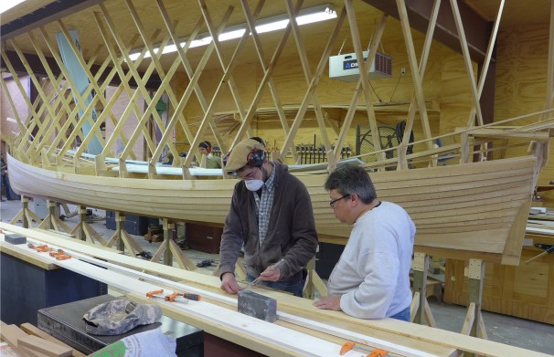 Students Ben Davant, left, and Mike Podgajski shape the final plank for the pilot gig. Photo courtesy of the Great Lakes Boat Building School. 