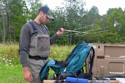 Graeme Zaparzynski uses a radio antennae to locate a brook trout in Cedar Creek that carries a tiny transmitter in its abdomen. Photo by Howard Meyerson