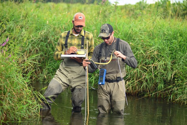 Justin Wegner, left, and Graeme Zaparzynski take ambient water temperature readings at a random spot downstream from where they located a tagged brook trout. Photo by Howard Meyerson.